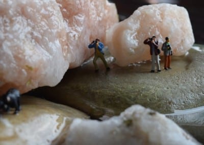 tiny figures standing on a rock taking photos