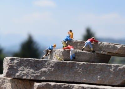 four tiny figures climbing rocks