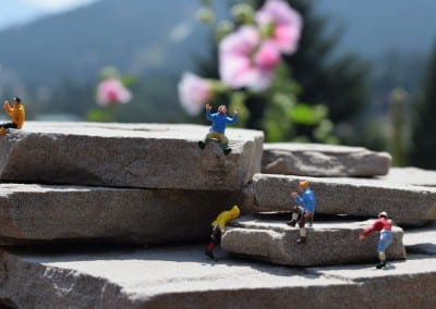 5 tiny figures climbing rocks