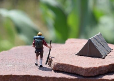 a tiny figure with a tent on a rock